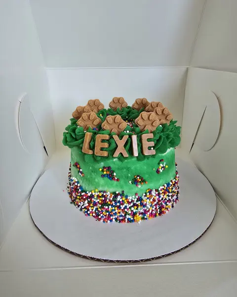 Green birthday cake with LEXIE piped on it and blue ruffles