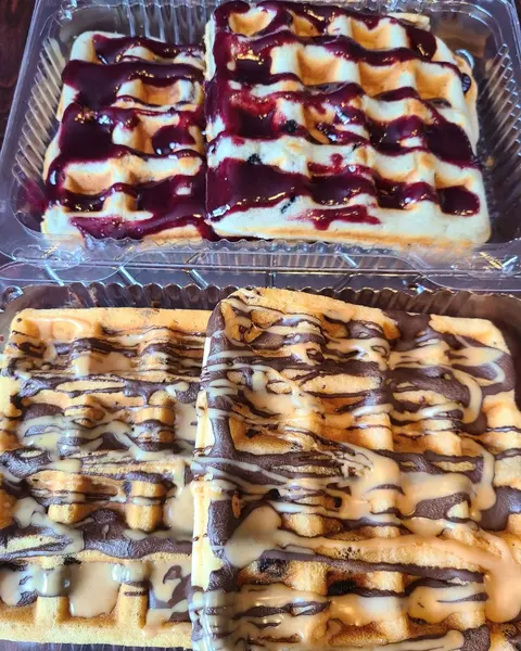 Trays of baked bars with a purple berry layer and chocolate-style drizzle