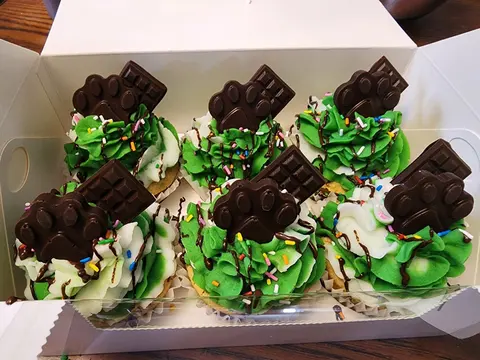 Box of pupcakes with green and white frosting and chocolate paw toppers