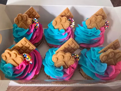 Pupcakes with pink and blue frosting topped with mini waffles and paw cookies