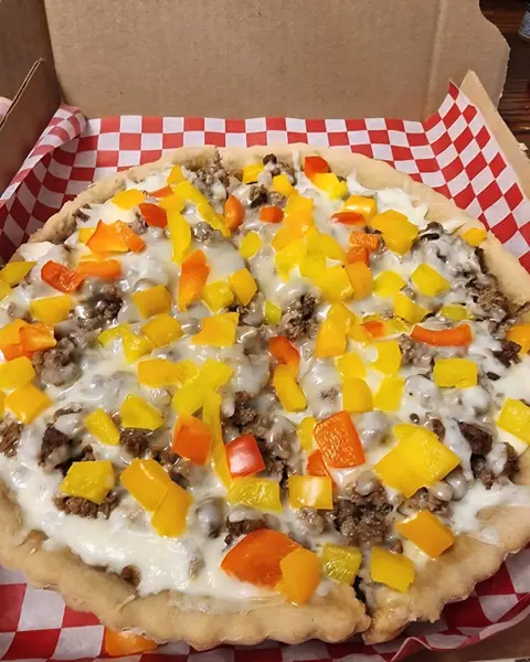 Pizza-style dinner topped with ground meat and diced yellow and orange peppers in a checked box